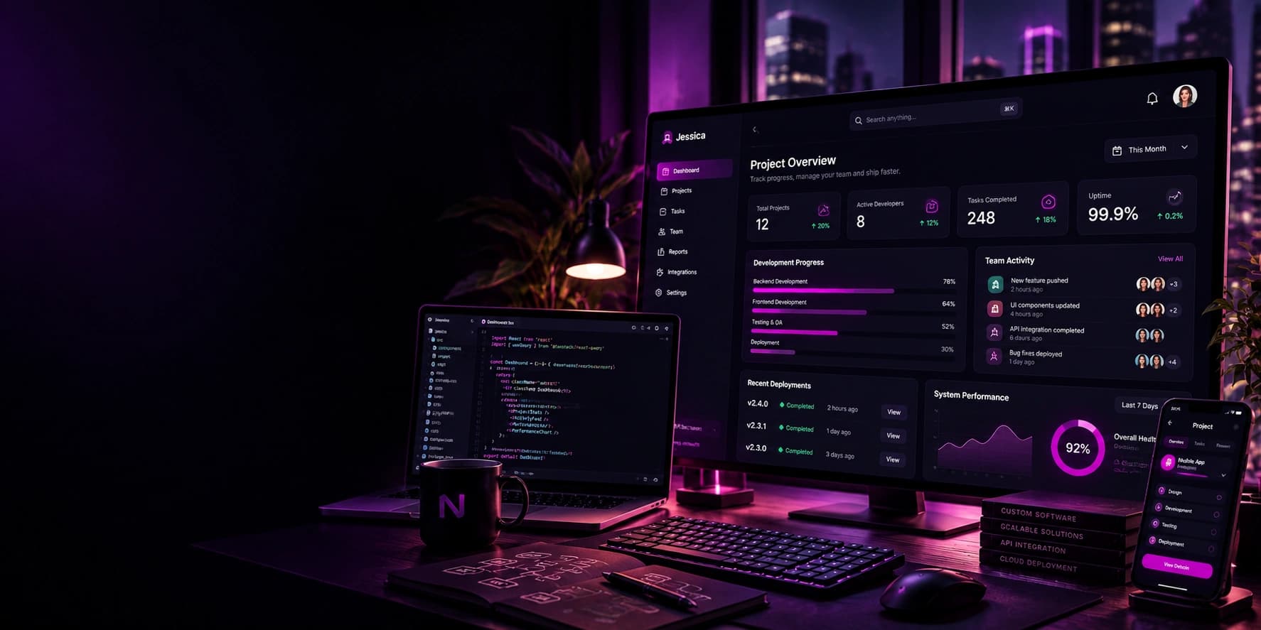 A monitor showing a project delivery dashboard, with a laptop open on source code beside it.